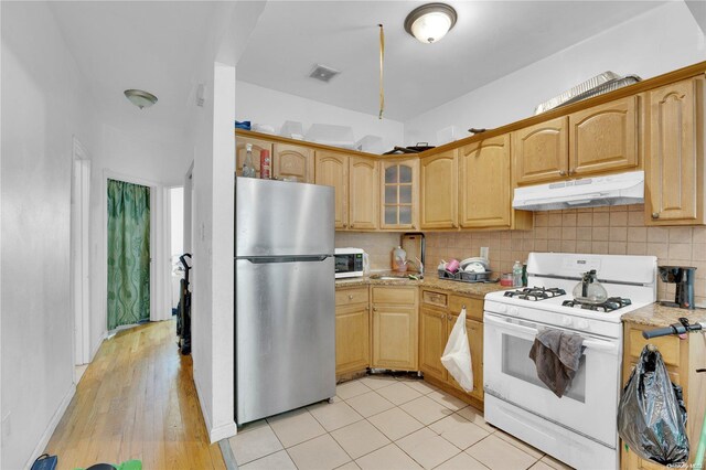 kitchen featuring decorative backsplash, light brown cabinetry, white appliances, sink, and light hardwood / wood-style flooring