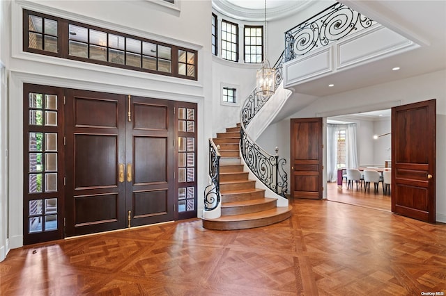 foyer featuring a chandelier, a high ceiling, and parquet flooring