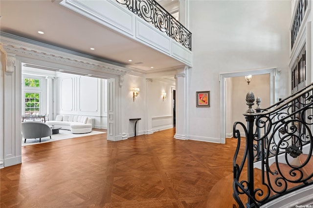 foyer entrance featuring parquet flooring, crown molding, a high ceiling, and an inviting chandelier