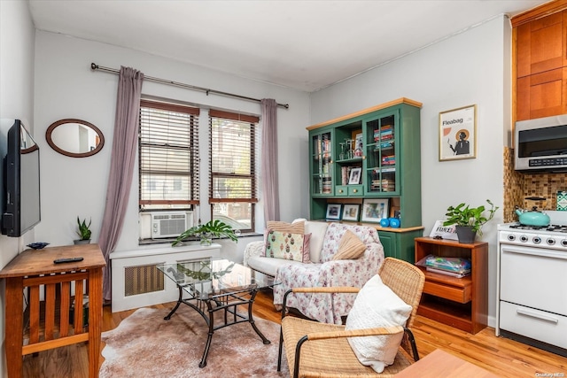 living area with cooling unit, radiator, and light hardwood / wood-style flooring