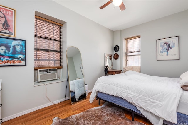 bedroom with ceiling fan, cooling unit, and wood-type flooring