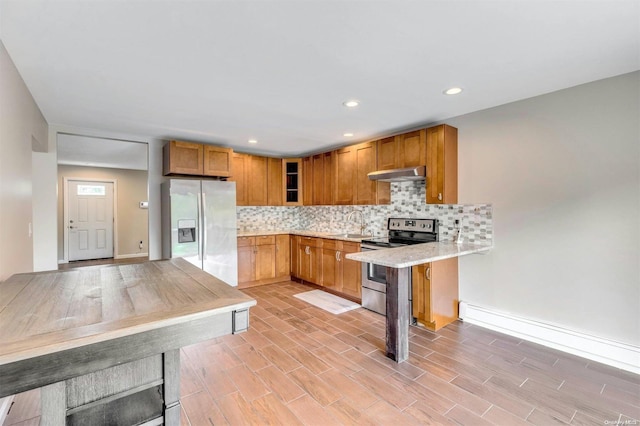 kitchen with kitchen peninsula, backsplash, stainless steel appliances, a baseboard radiator, and light hardwood / wood-style floors