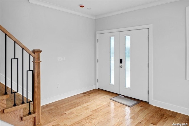 foyer with a wealth of natural light, french doors, ornamental molding, and light wood-type flooring