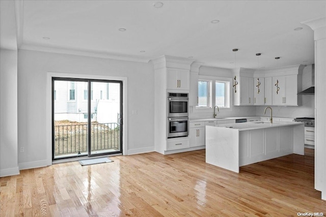 kitchen with white cabinetry, a wealth of natural light, and a kitchen island with sink