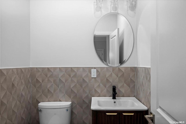 bathroom with vanity, tile walls, and toilet