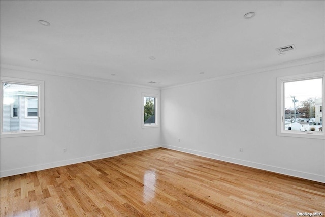 empty room featuring light wood-type flooring and crown molding