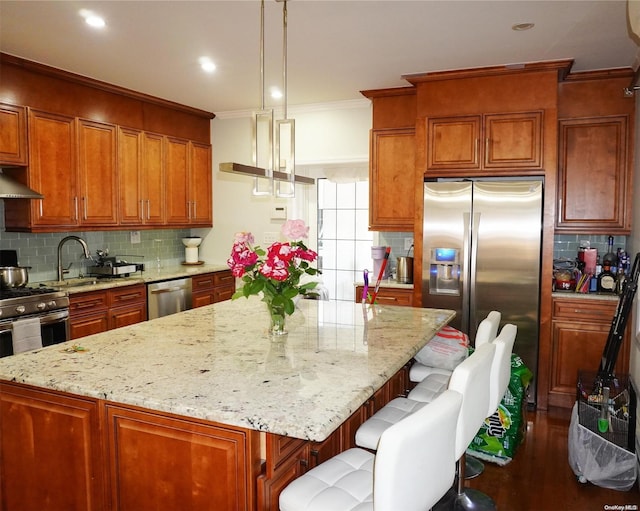 kitchen with a center island, hanging light fixtures, dark wood-type flooring, stainless steel appliances, and decorative backsplash