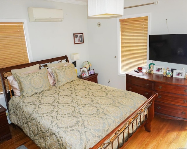 bedroom with an AC wall unit, crown molding, and wood-type flooring