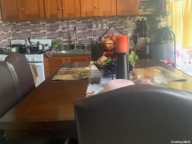 kitchen featuring backsplash, white gas range oven, and sink