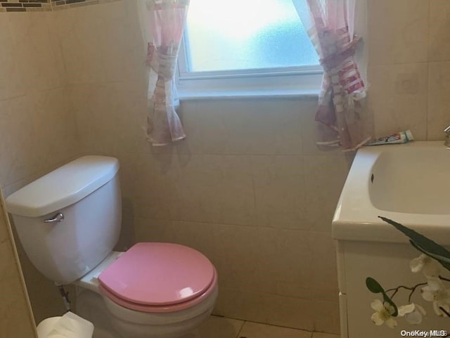 bathroom with tile patterned flooring, vanity, toilet, and tile walls