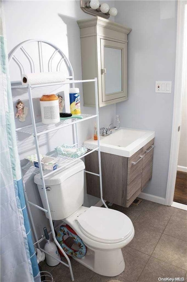 bathroom with tile patterned flooring, vanity, and toilet