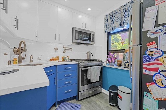 kitchen featuring blue cabinetry, sink, stainless steel appliances, light hardwood / wood-style flooring, and white cabinets