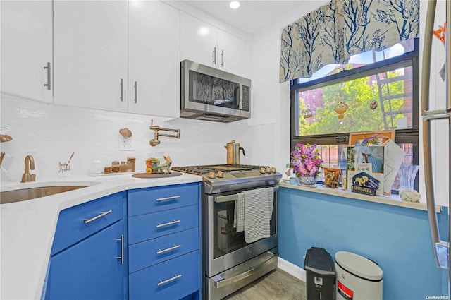 kitchen with sink, hardwood / wood-style flooring, blue cabinetry, white cabinetry, and stainless steel appliances