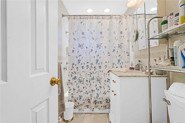 full bathroom with shower / bath combo, tile patterned flooring, toilet, vanity, and tile walls