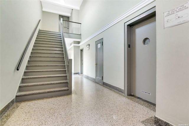 stairway featuring a towering ceiling and elevator