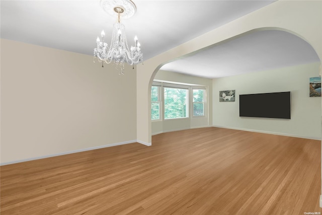 unfurnished living room with a notable chandelier and light hardwood / wood-style flooring