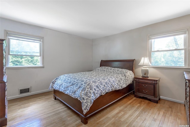 bedroom with multiple windows and light hardwood / wood-style flooring