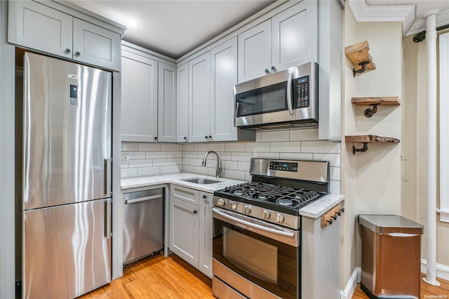 kitchen featuring sink, stainless steel appliances, tasteful backsplash, light stone counters, and light hardwood / wood-style floors