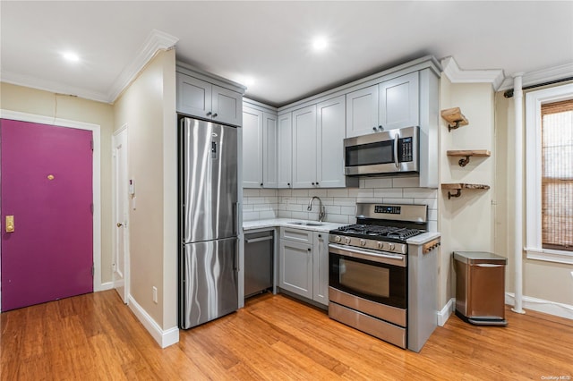 kitchen featuring gray cabinetry, ornamental molding, stainless steel appliances, and light hardwood / wood-style flooring