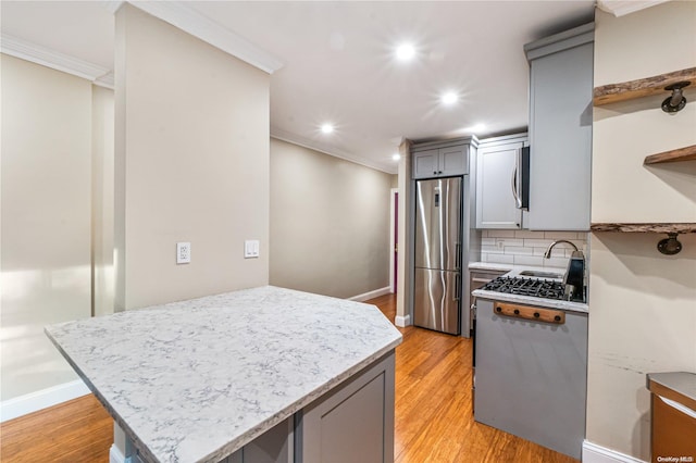 kitchen with gray cabinets, light hardwood / wood-style flooring, stainless steel appliances, and crown molding