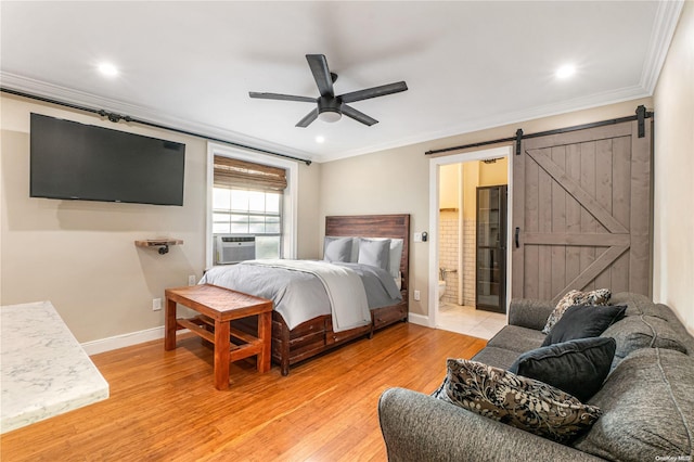 bedroom featuring a barn door, ceiling fan, light hardwood / wood-style flooring, and ensuite bath