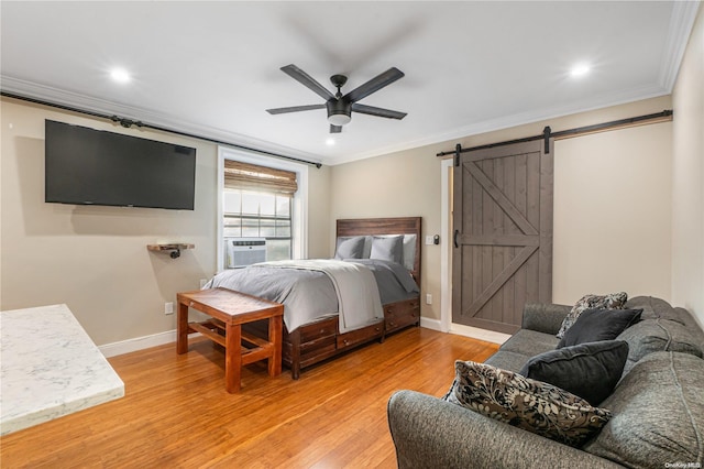 bedroom featuring a barn door, ceiling fan, crown molding, and light wood-type flooring