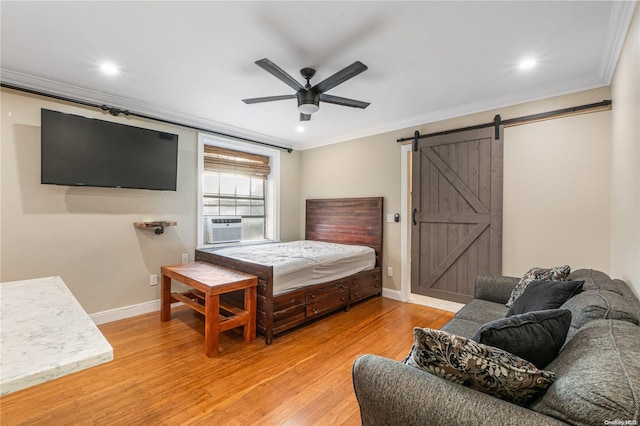 bedroom featuring ceiling fan, a barn door, light hardwood / wood-style floors, and ornamental molding