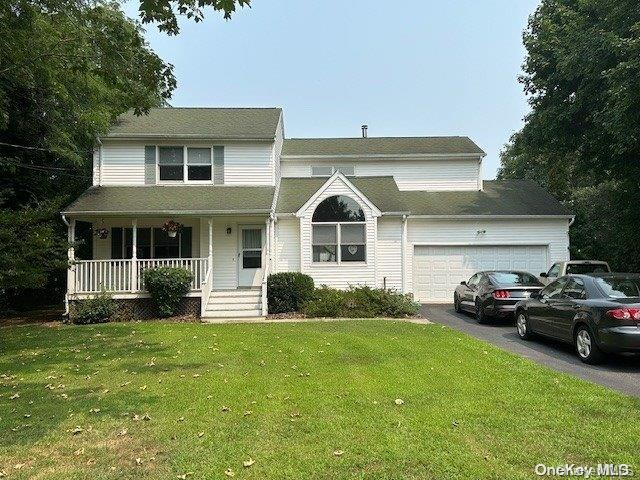 front of property with covered porch, a garage, and a front lawn