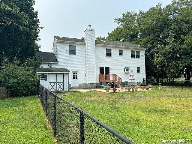 back of house featuring a lawn and a storage shed