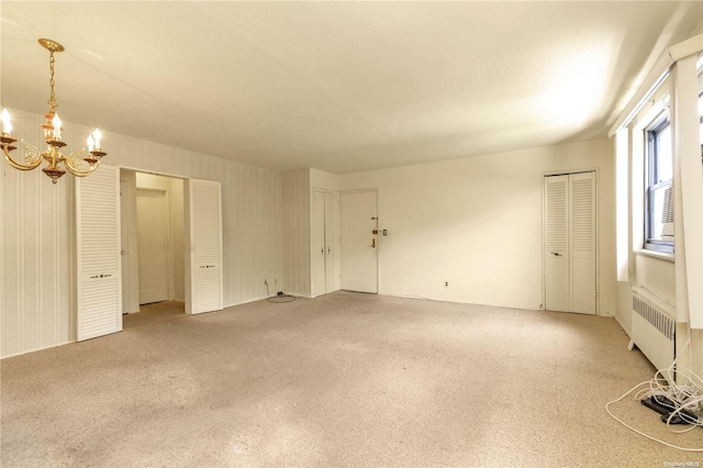 unfurnished room featuring a notable chandelier and radiator heating unit