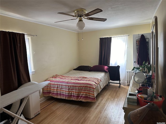 bedroom with radiator, ceiling fan, ornamental molding, and light wood-type flooring