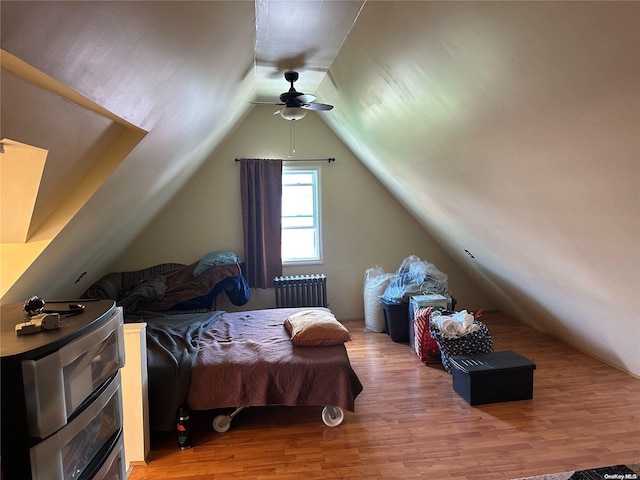 bedroom with radiator heating unit, hardwood / wood-style flooring, ceiling fan, and lofted ceiling