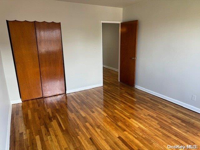 unfurnished bedroom featuring dark hardwood / wood-style floors and a closet