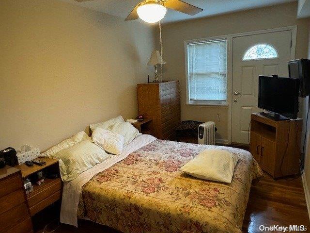 bedroom with ceiling fan, dark hardwood / wood-style flooring, and radiator heating unit