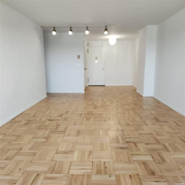 spare room with light parquet flooring and track lighting