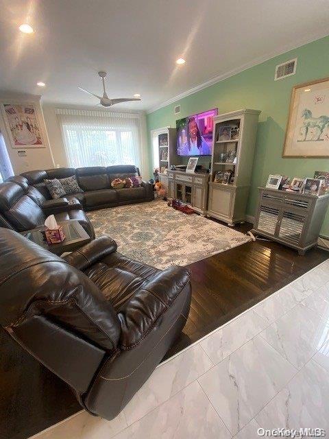 living room featuring hardwood / wood-style flooring, ceiling fan, and crown molding