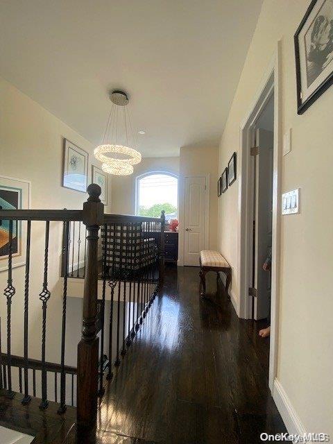 corridor with hardwood / wood-style floors and a notable chandelier