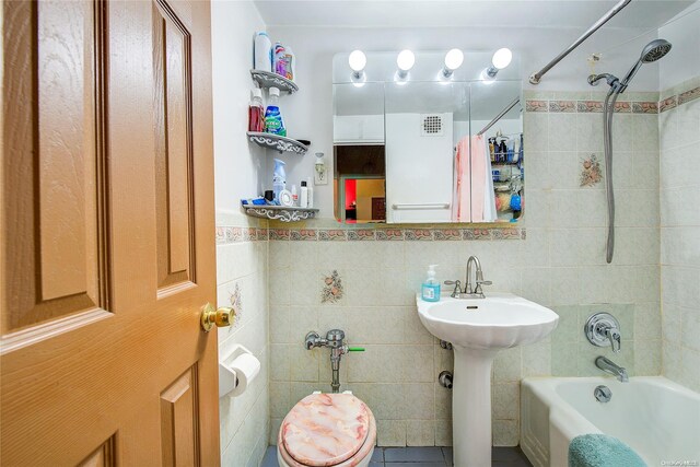 full bathroom with sink, tile patterned flooring, tile walls, toilet, and shower / tub combo