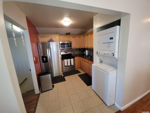 kitchen with appliances with stainless steel finishes, backsplash, stacked washing maching and dryer, light brown cabinetry, and light tile patterned floors