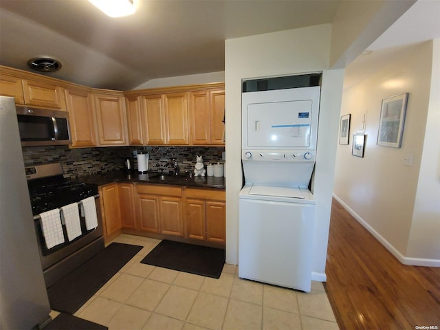 kitchen with backsplash, stainless steel appliances, sink, stacked washer / dryer, and light tile patterned flooring