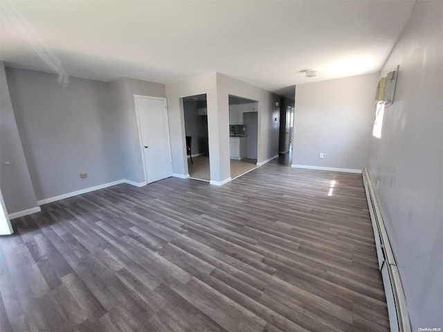 empty room featuring dark wood-type flooring and a baseboard heating unit