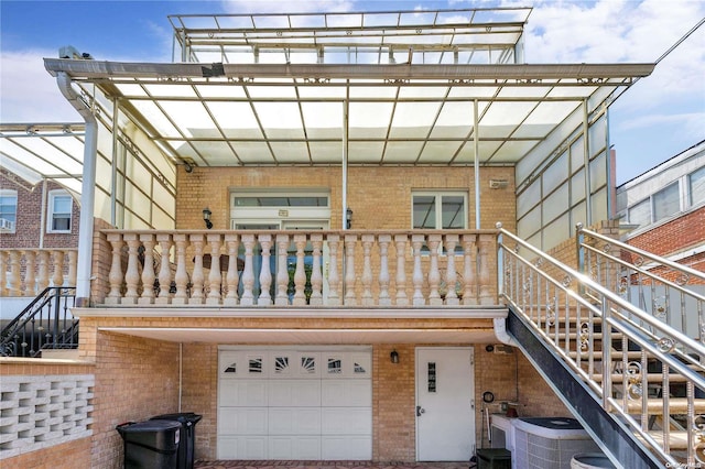 back of property featuring a balcony, a garage, and central AC unit