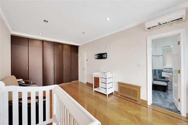 bedroom with a wall mounted air conditioner and light parquet floors