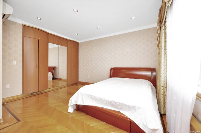 bedroom featuring crown molding, light parquet flooring, and a wall mounted air conditioner