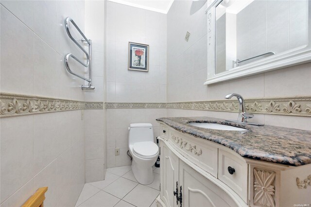 bathroom with tile patterned floors, vanity, toilet, and tile walls