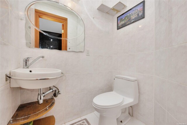 bathroom with sink, tasteful backsplash, tile patterned floors, toilet, and tile walls