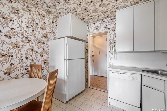 kitchen featuring light tile patterned floors, white cabinets, white appliances, and sink