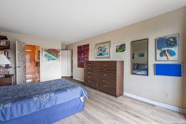 bedroom with ensuite bath and light hardwood / wood-style flooring