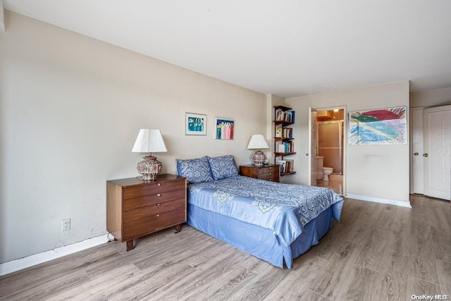 bedroom with light hardwood / wood-style flooring and ensuite bath