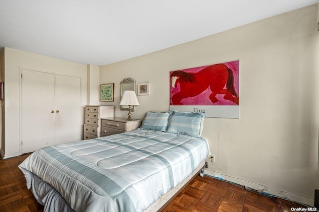 bedroom featuring dark parquet flooring and a closet